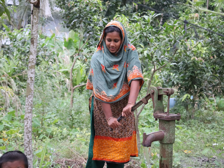 Community member operates a hand-pump for water, a result of locally led humanitarian aid, installed after 2024 floods.